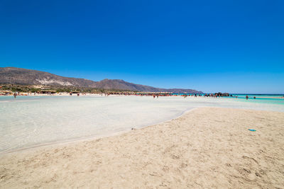 Scenic view of beach against clear blue sky