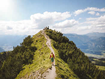 Rear view of woman walking on mountain against sky