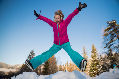 Man with arms outstretched on snow against sky