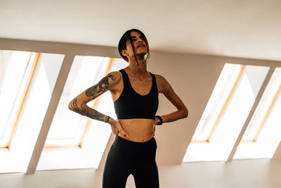 Young woman exercising while standing at gym