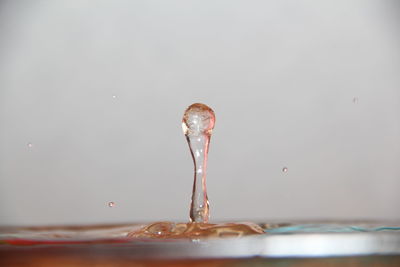 Close-up of drop falling in water against gray background