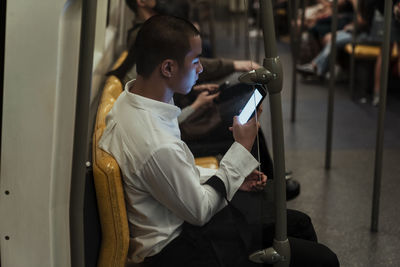 Rear view of man using mobile phone while sitting in train