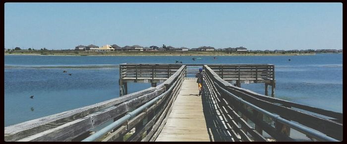 Pier in sea against blue sky