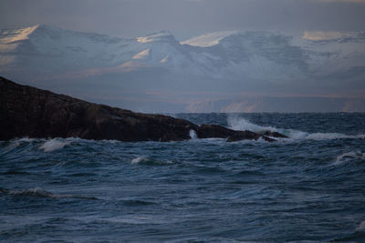 Scenic view of sea and snowcapped mountains against sky