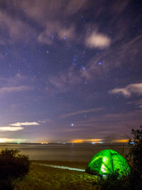 Scenic view of illuminated field against sky at night