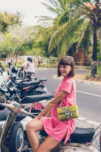 Portrait of women sitting on sidewalk against trees