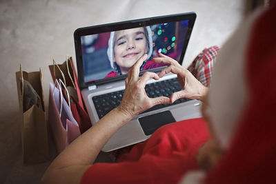 Safe online christmas celebration. senior woman in santa red hat celebrating with family virtually