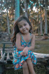 Portrait of young kid sitting on bench at park