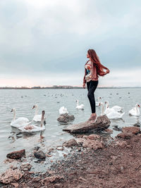 Woman standing at beach against cloudy sky