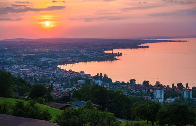 High angle view of townscape by sea against sky during sunset