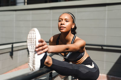 Full length of young woman exercising in city during sunny day