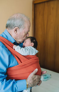 Great-grandfather carrying baby in a baby sling