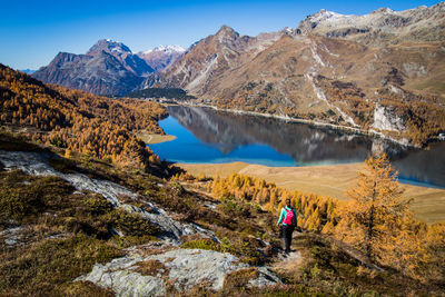 Rear view of woman walking on mountain by lake