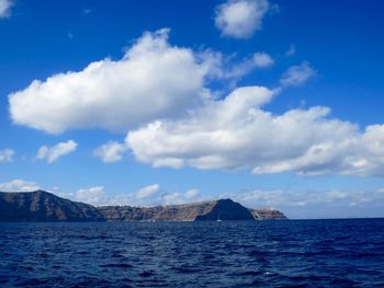 View of calm blue sea against rocky mountains