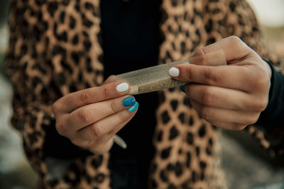 Woman rolling marijuana cigarette outdoors