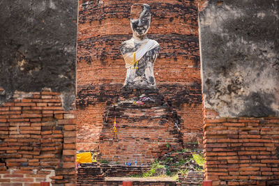 Statue against brick wall