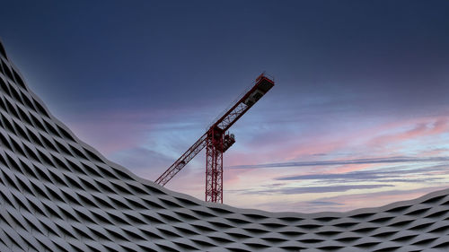 View of a construction crane with a colorful sky in the background