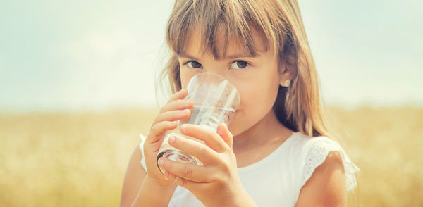 Portrait of girl drinking water at farm