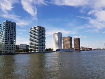 Buildings by river against sky in city