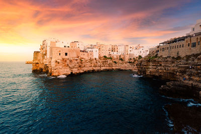 View of sea and buildings against sky at sunset