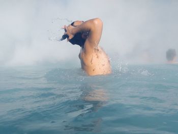 High angle view of young woman splashing water in sea
