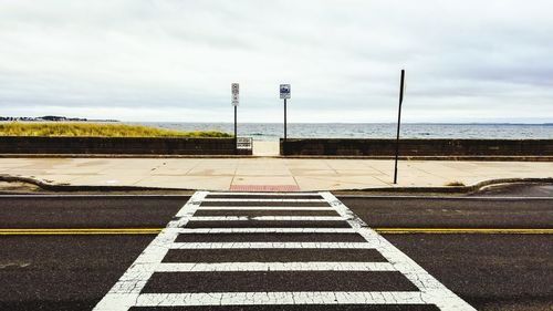 Road sign on street against sky