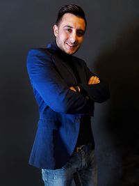 Portrait of young man standing against black background