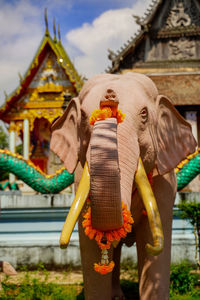 Wildlife elephant sculpture decorated with flower, outdoor in front of the temple or wat.