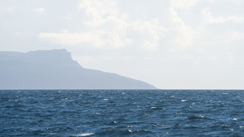 Scenic view of sea and mountains against sky