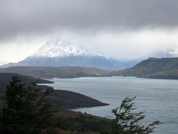 Scenic view of mountains and lake against cloudy sky