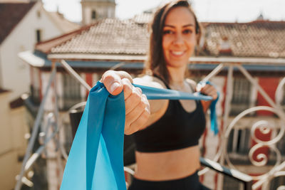 Young sporty fit woman exercising with elastic bands on her rooftop