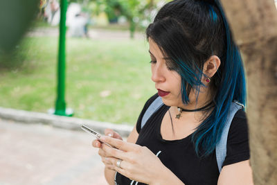 View of a beautiful young blue-haired latina university student looking at her social networks