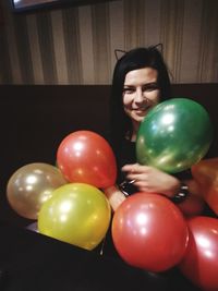 Portrait of woman with balloons on table at home