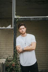 Portrait of young man standing against wall