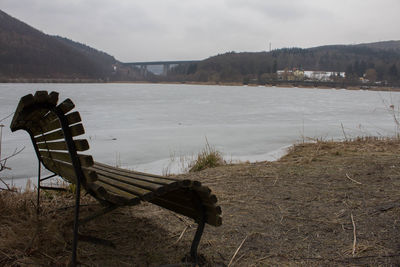 Chair on shore against sky