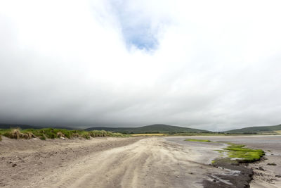 Dirt road passing through landscape against sky