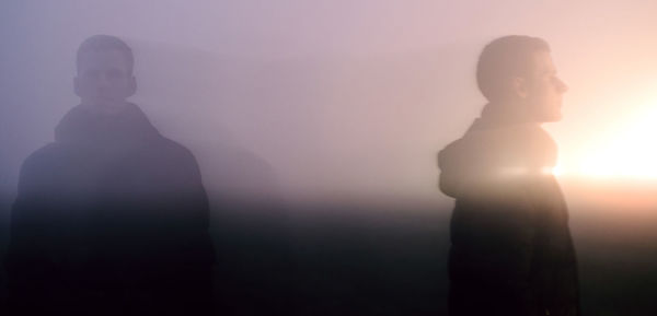 Silhouette woman standing on fog against sky during sunset