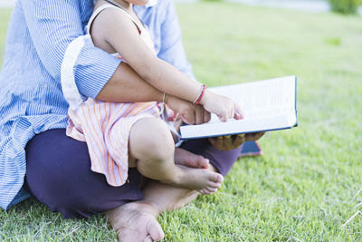 Midsection of woman using laptop while sitting on field