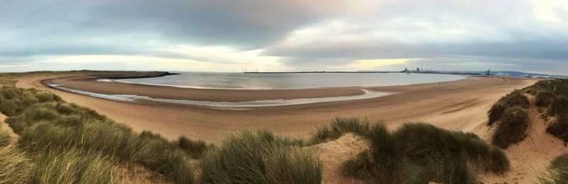 Panoramic view of sand dunes against sky