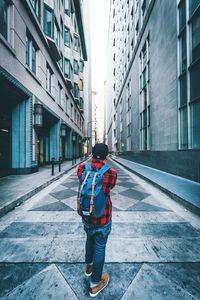 Rear view of man standing on walkway amidst buildings