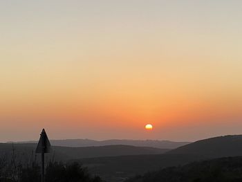 Silhouette person standing on mountain against sky during sunset