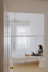 A european woman in a gray linen robe is working on a laptop at home or resting. a millennial woman