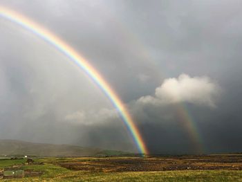 Scenic view of rainbow over landscape against sky