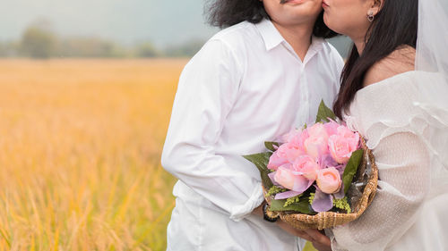 Midsection of woman holding flower bouquet on land