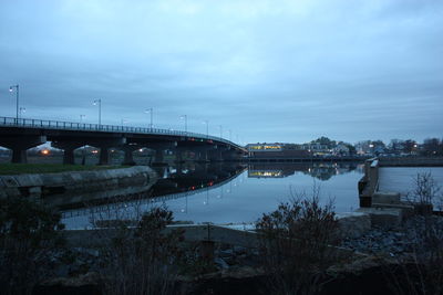 Bridge over river against sky in city