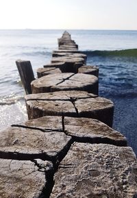 Wooden posts in sea against sky