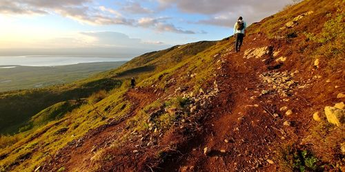 Switchbacks, hikers climb mt, against sky. alaska