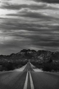 Road leading towards mountain against sky