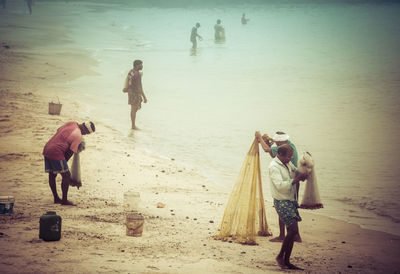 Rear view of people walking on beach