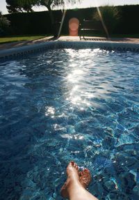 Low section of woman standing in swimming pool